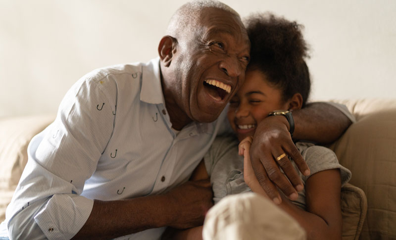 Grandpa hugging granddaughter laughing on the couch